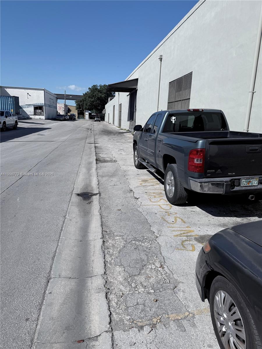 A grey pickup truck is parked on an asphalt lot next to a white building — 0 NW 21 Terrace & 12th Ave, Miami FL 33127, MIAMI, FL