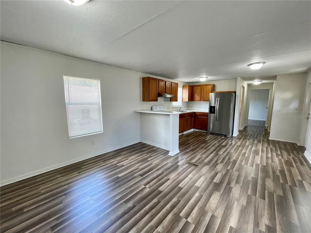 An open-concept kitchen and living area features wood-look flooring and stainless steel appliances — 6328 EUGENE ACRES LANE, GIBSONTON, FL