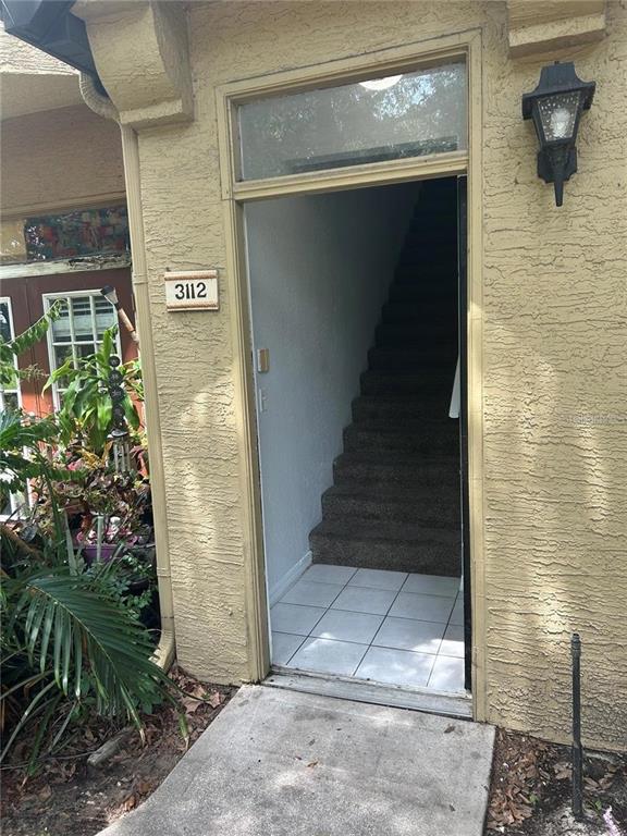 An exterior view shows an open doorway leading to an interior staircase with carpeted steps — 6424 RALEIGH STREET UNIT 3112, ORLANDO, FL