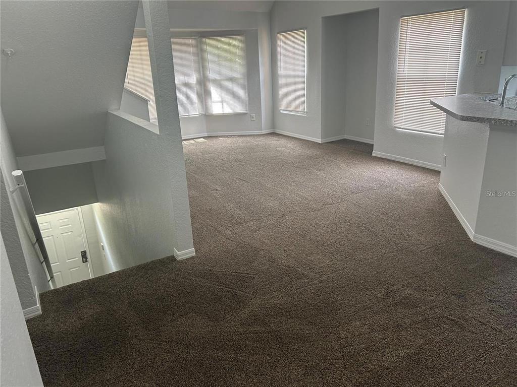 An interior view shows a carpeted living area with a staircase leading to a lower level — 6424 RALEIGH STREET UNIT 3112, ORLANDO, FL