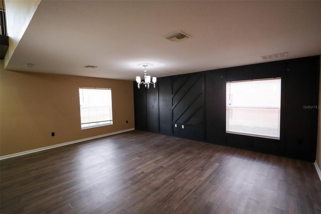 A living room features wood-look flooring, a tan wall, and a black accent wall — 15040 SW 39TH CIRCLE, OCALA, FL
