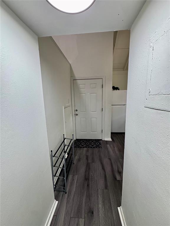 A hallway with wood-look flooring leads to a white door and a shoe rack — 12315 TOUCHTON DRIVE UNIT 90, TAMPA, FL