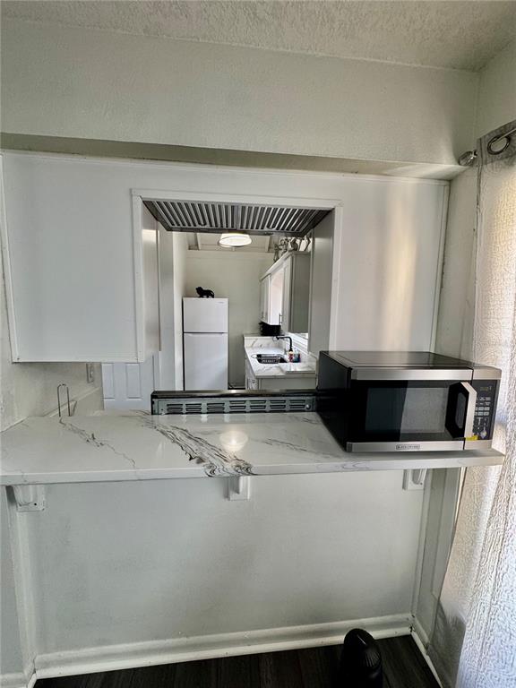 A kitchen pass-through window overlooks a kitchen with white cabinets and a marble-patterned countertop — 12315 TOUCHTON DRIVE UNIT 90, TAMPA, FL