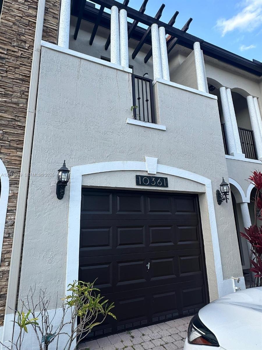 The exterior of a two-story townhouse features a dark garage door and white columns — 10361 NW 32nd Ter # 0, Doral FL 33172, DORAL, FL