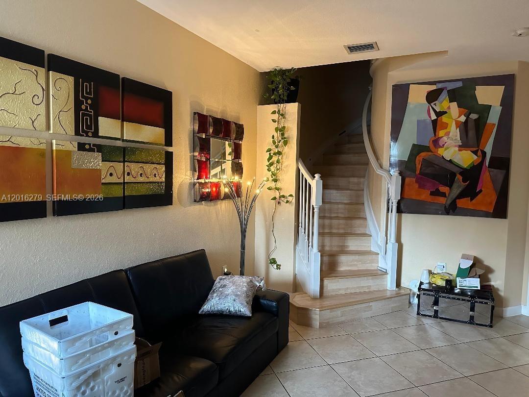 A living room features a black leather sofa, tiled floors, and a staircase with railing — 10361 NW 32nd Ter # 0, Doral FL 33172, DORAL, FL