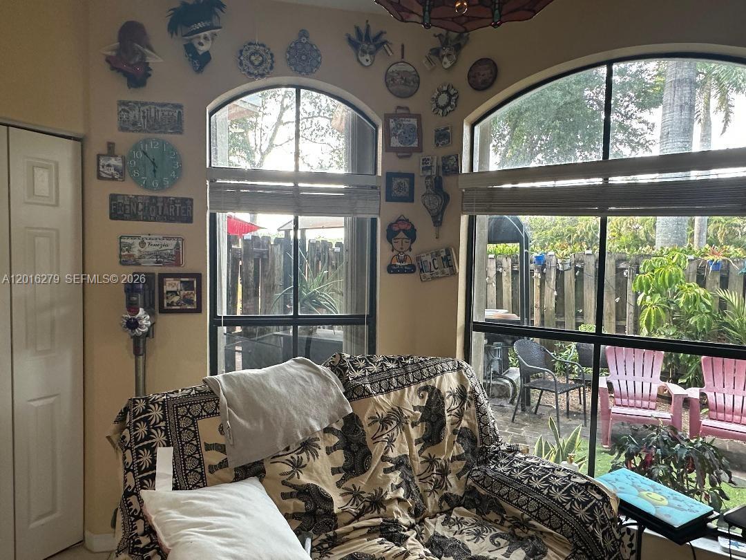 A living area features a patterned sofa, wall-mounted decor, and large windows overlooking a backyard — 10361 NW 32nd Ter # 0, Doral FL 33172, DORAL, FL