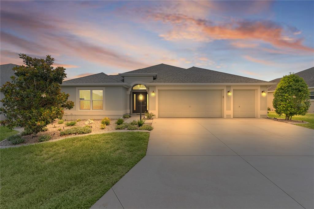 A single-story house with a gray exterior, a three-car garage, and a landscaped front yard — 5833 ABNEY AVENUE, THE VILLAGES, FL