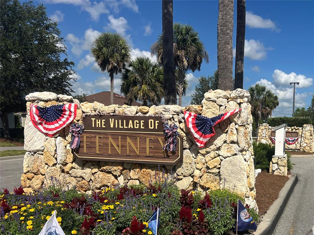 A stone monument sign for The Village of Fenney is decorated with patriotic bunting — 5833 ABNEY AVENUE, THE VILLAGES, FL