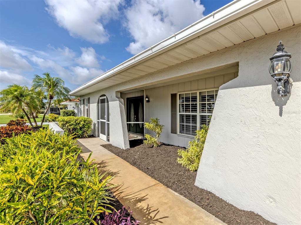 A view of a house exterior featuring a walkway, landscaping, and a covered entryway — 1720 SANDY COURT, VENICE, FL
