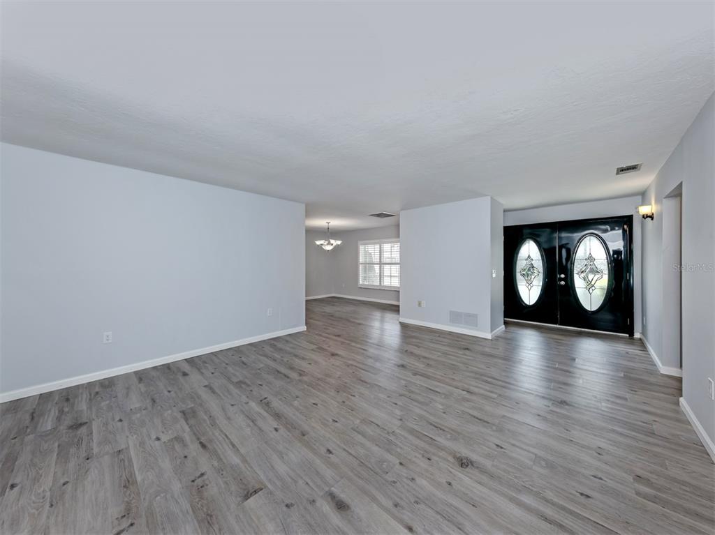An open living area features light gray walls, wood-look flooring, and black double entry doors — 1720 SANDY COURT, VENICE, FL