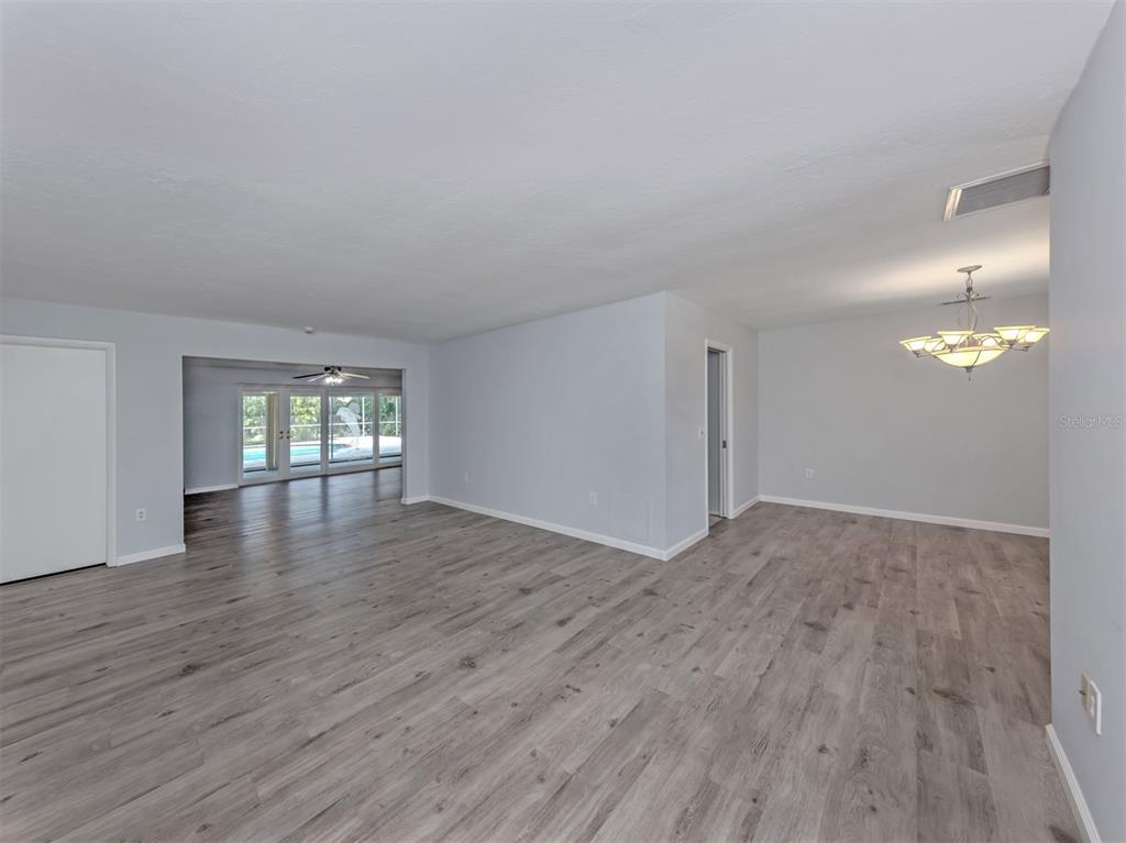 An open-concept living and dining area features light gray walls and wood-look laminate flooring — 1720 SANDY COURT, VENICE, FL