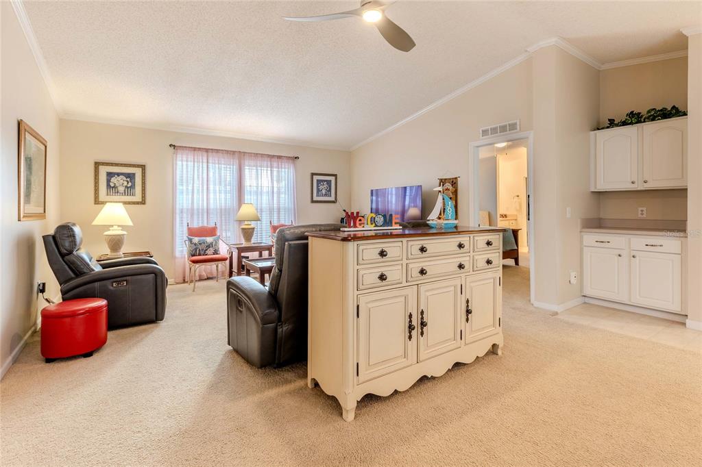 A living room features beige carpet, two leather recliners, a white sideboard, and white cabinetry — 2100 KINGS HIGHWAY UNIT 690, PORT CHARLOTTE, FL