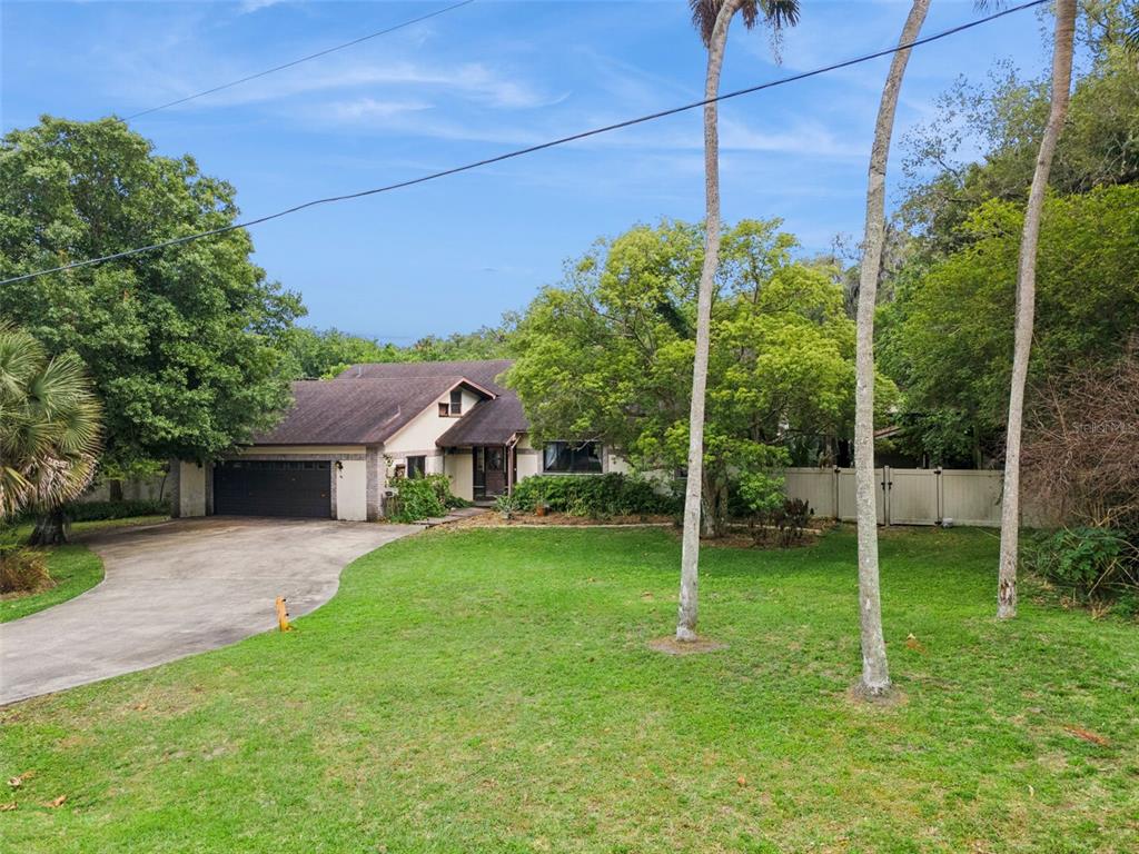 A single-story house with a two-car garage, a concrete driveway, and palm trees in front — 3443 PARKLAND STREET, TITUSVILLE, FL