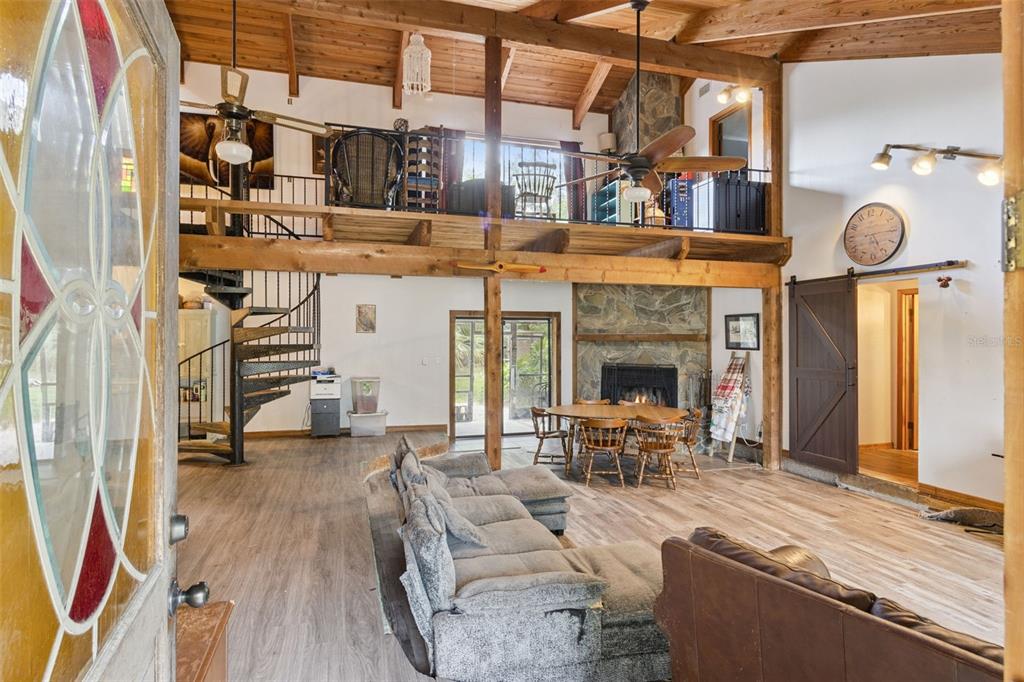 A living room with a spiral staircase, a stone fireplace, and a wooden loft area — 3443 PARKLAND STREET, TITUSVILLE, FL