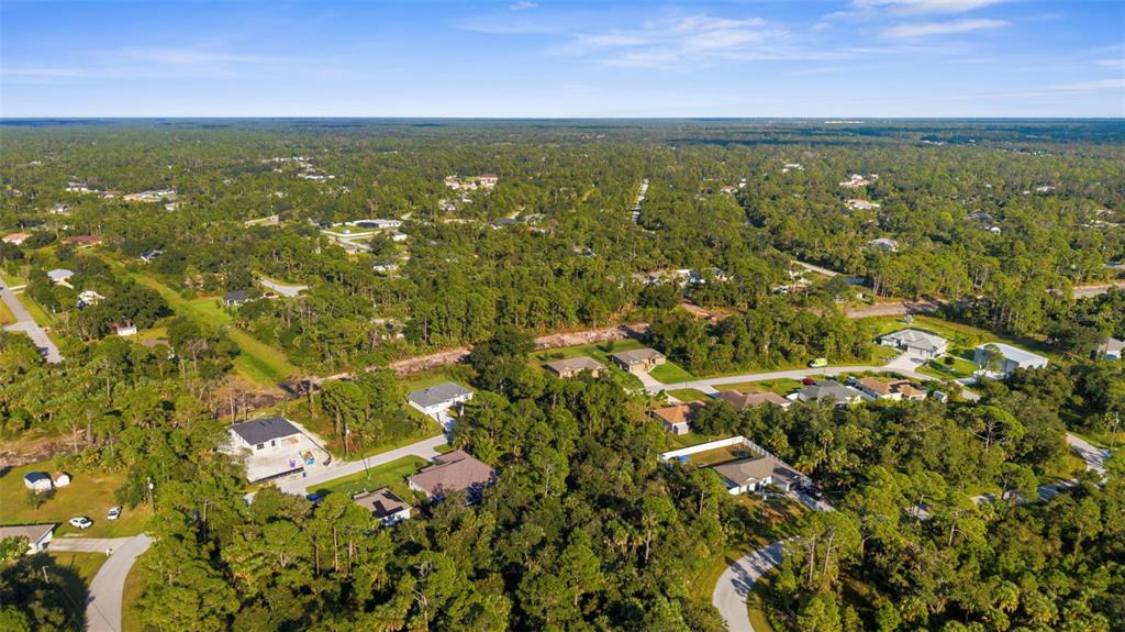An aerial view shows scattered houses nestled within a dense, wooded residential area — 18 BECKWITH AVENUE, NORTH PORT, FL