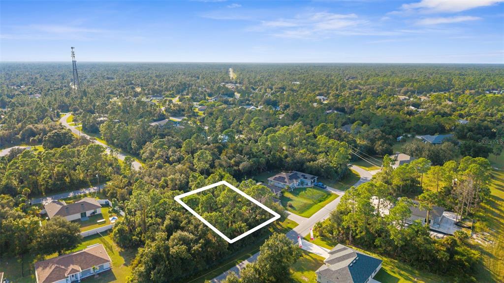 An aerial view shows a vacant, rectangular lot outlined in white within a wooded neighborhood — 18 BECKWITH AVENUE, NORTH PORT, FL