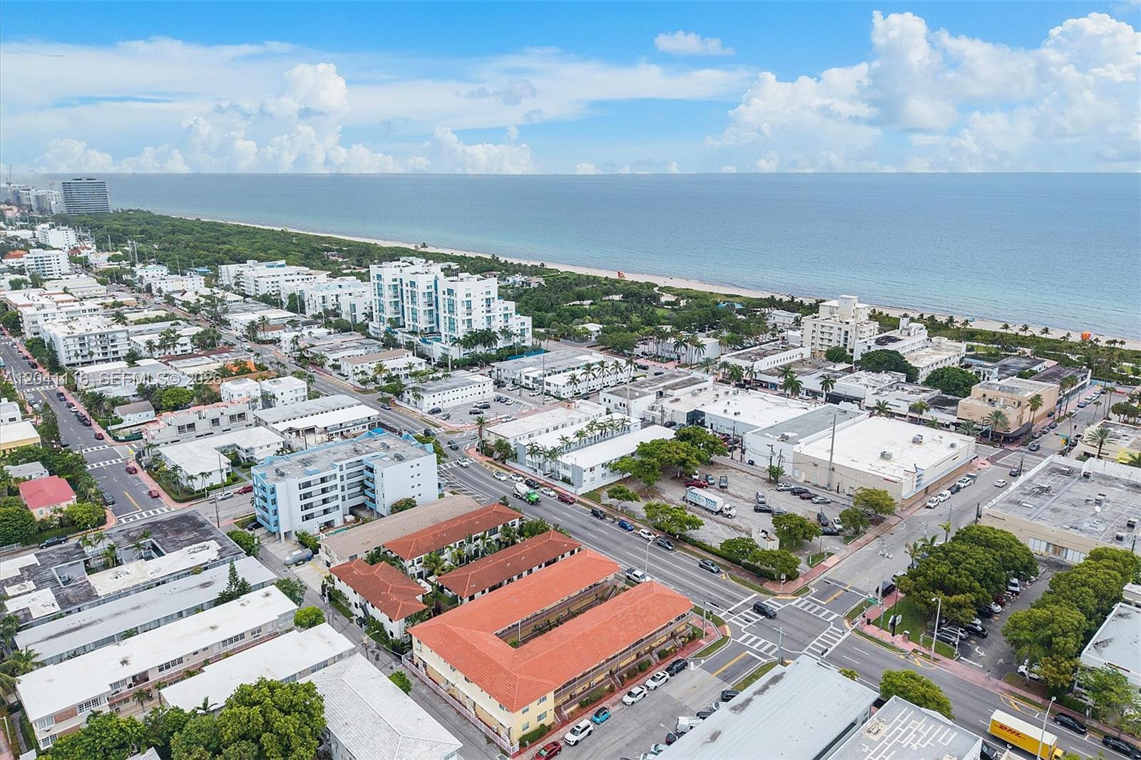 An aerial view shows a coastal city with low-rise buildings, streets, and a sandy beach — 7400 Harding Ave # 20, Miami Beach FL 33141, MIAMI BEACH, FL