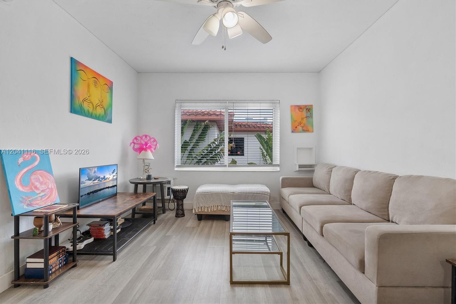 A living room features a beige sofa, glass coffee table, media console, and light flooring — 7400 Harding Ave # 20, Miami Beach FL 33141, MIAMI BEACH, FL