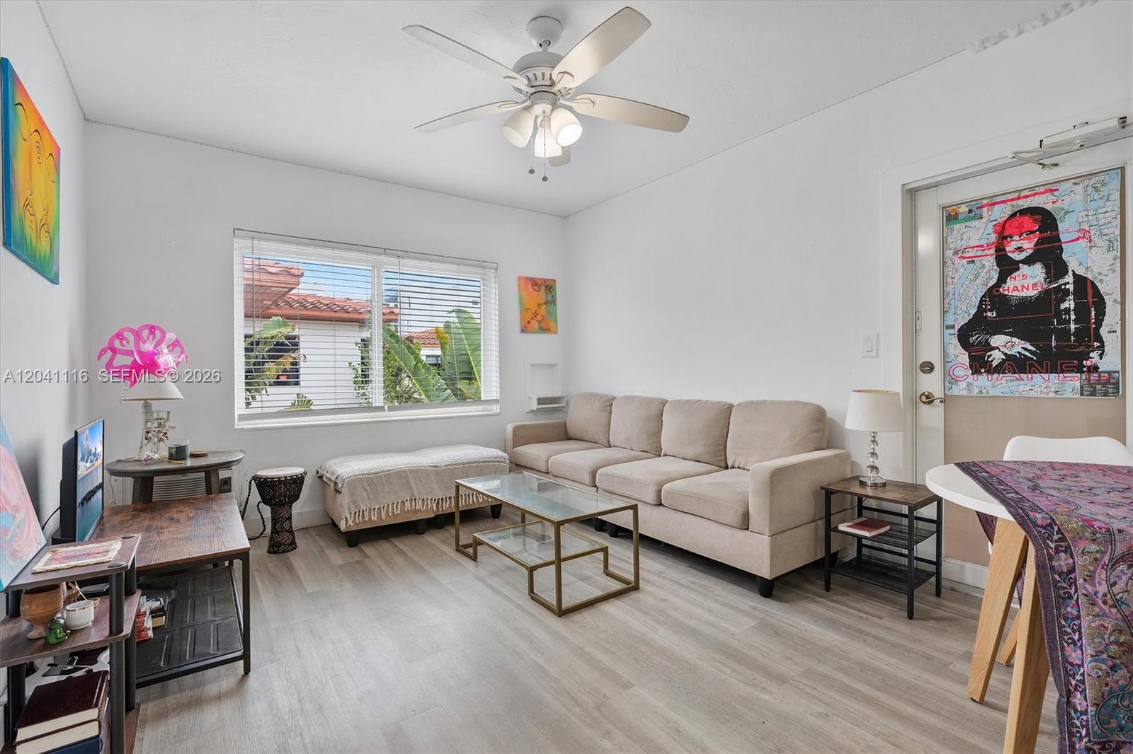 A living room features a beige sofa, glass coffee table, ceiling fan, and light flooring — 7400 Harding Ave # 20, Miami Beach FL 33141, MIAMI BEACH, FL