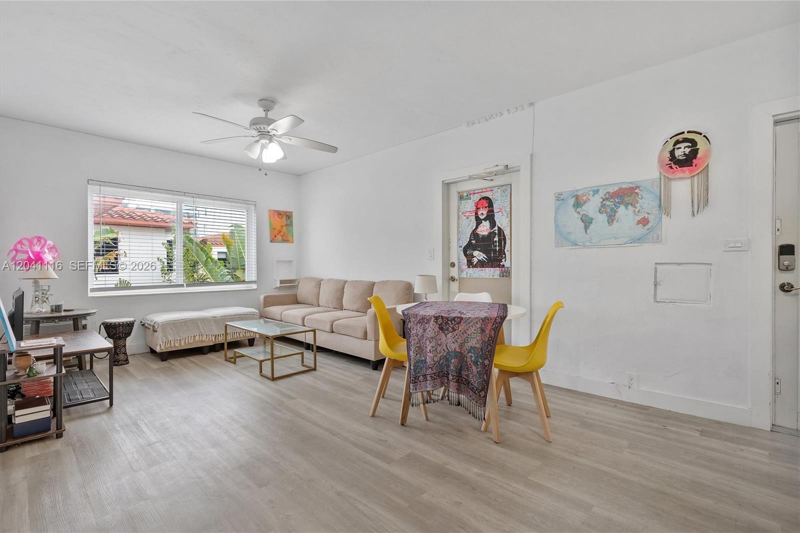 A bright living room features light wood flooring, a beige sofa, and yellow dining chairs — 7400 Harding Ave # 20, Miami Beach FL 33141, MIAMI BEACH, FL