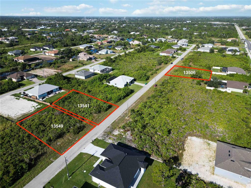 An aerial view shows three vacant residential lots outlined in red along a paved road — 13549 ABUTILON LANE, PORT CHARLOTTE, FL