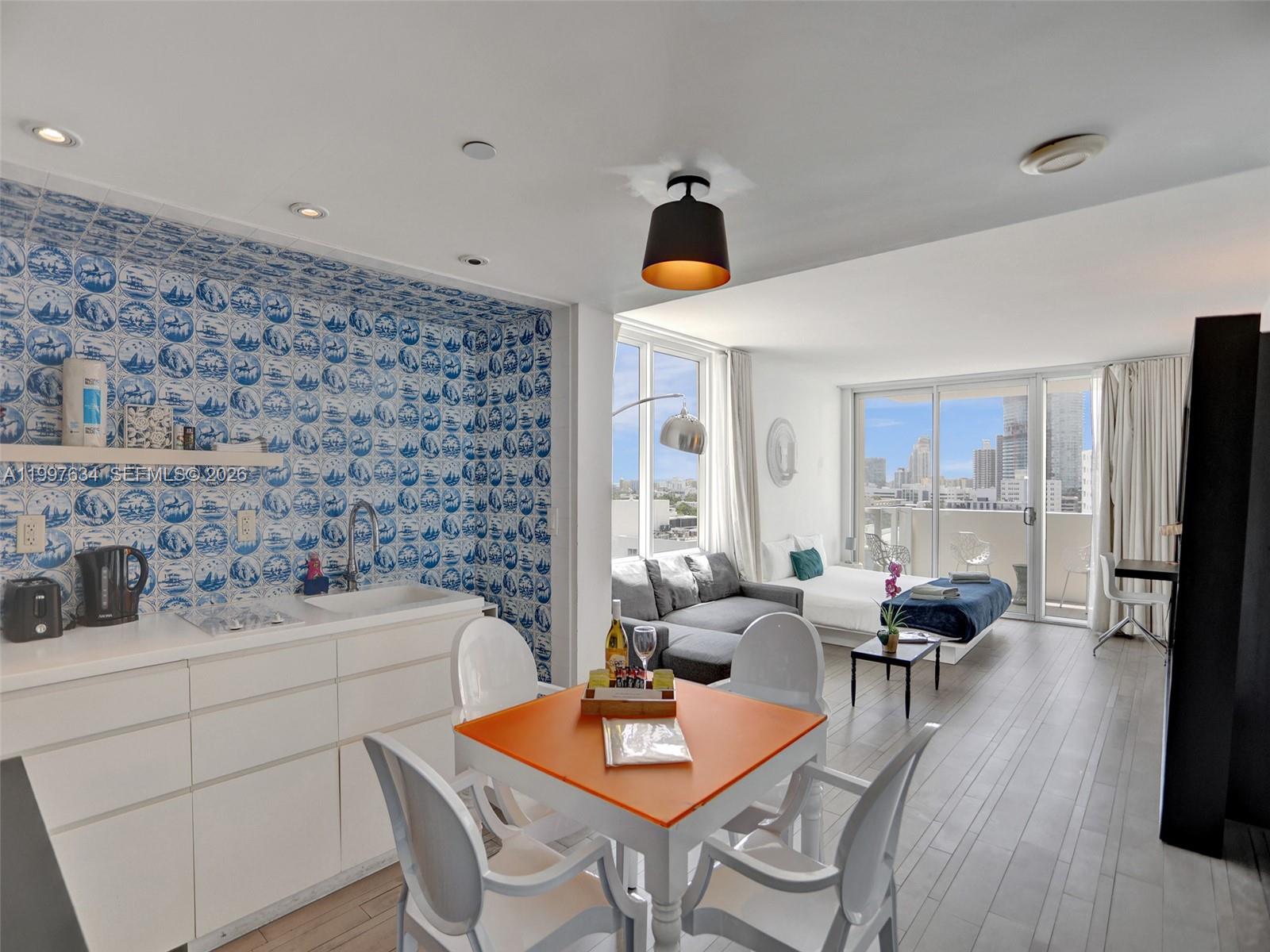 A studio apartment features a kitchen with blue patterned tile, a dining area, and bedroom — 1100 West Ave # 1101, Miami Beach FL 33139, MIAMI BEACH, FL