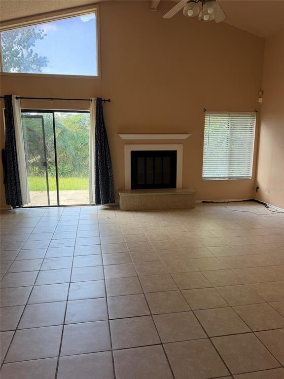 A living room with tile floors, a fireplace, sliding glass doors, and a vaulted ceiling — 6224 MISSON DRIVE, ORLANDO, FL