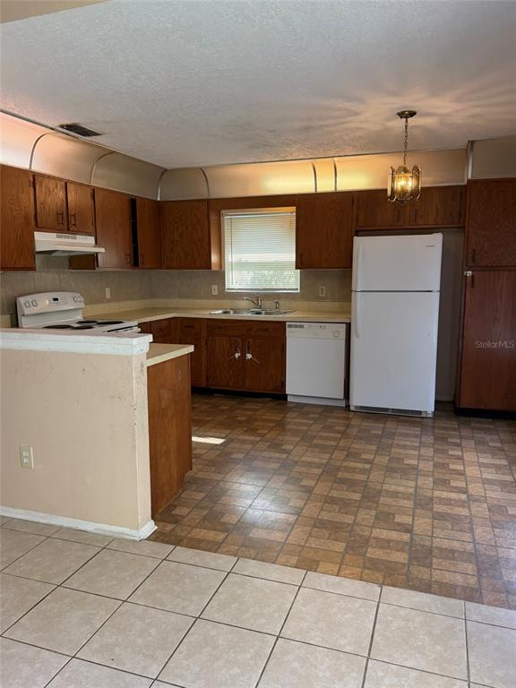 A kitchen with wood cabinets, white appliances, a tiled floor, and a breakfast bar — 6224 MISSON DRIVE, ORLANDO, FL