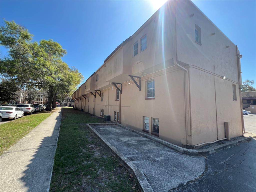 The exterior side of a multi-story apartment building features tan stucco walls and small windows — 914 SW 8TH AVENUE UNIT 44, GAINESVILLE, FL