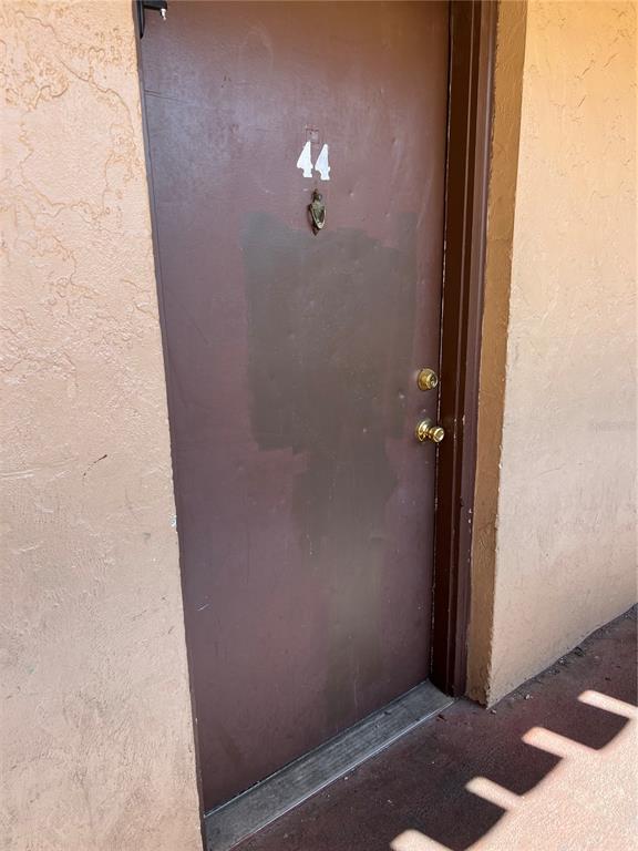 A brown exterior door labeled with the number 44 is set in a stucco wall — 914 SW 8TH AVENUE UNIT 44, GAINESVILLE, FL