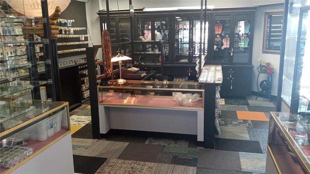 A retail store interior features glass display cases, dark cabinetry, and patterned carpet flooring — 1460 S MCCALL ROAD UNIT 3F, ENGLEWOOD, FL