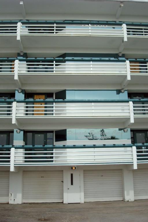 Exterior view of a multi-story building with balconies, glass windows, and ground-level garage doors — 1460 S MCCALL ROAD UNIT 3F, ENGLEWOOD, FL