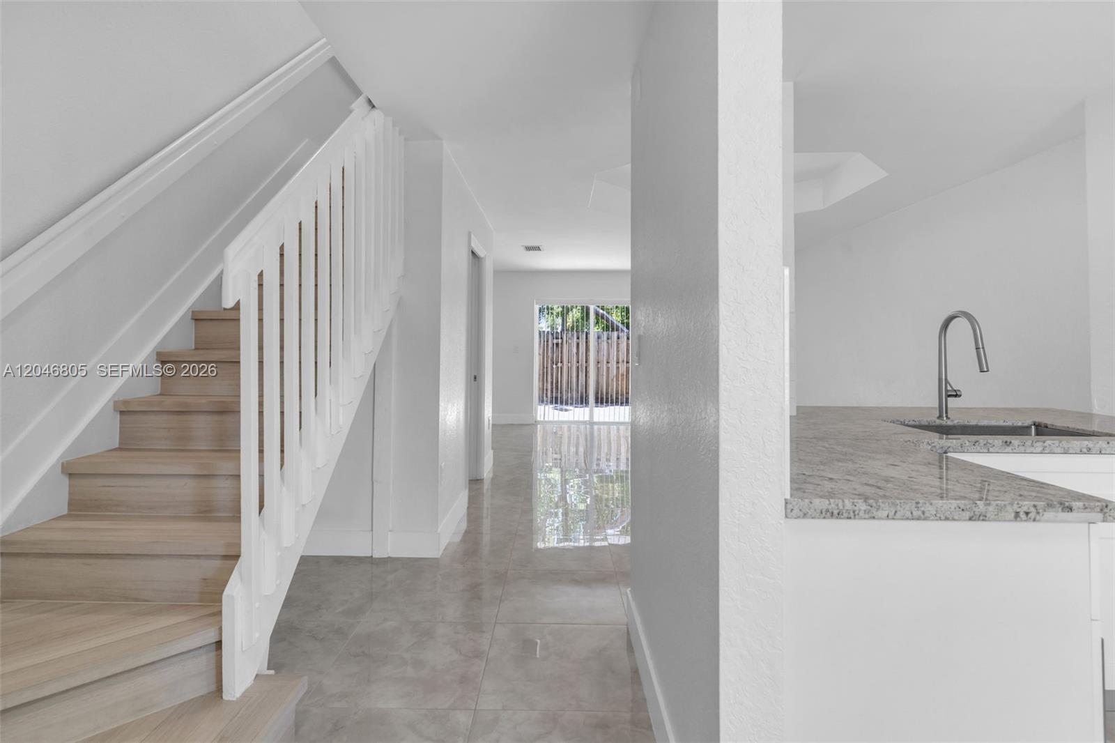 A staircase with wood treads leads up beside a kitchen counter and tiled floor — 14231 SW 120th Ct # 11, Miami FL 33186, MIAMI, FL