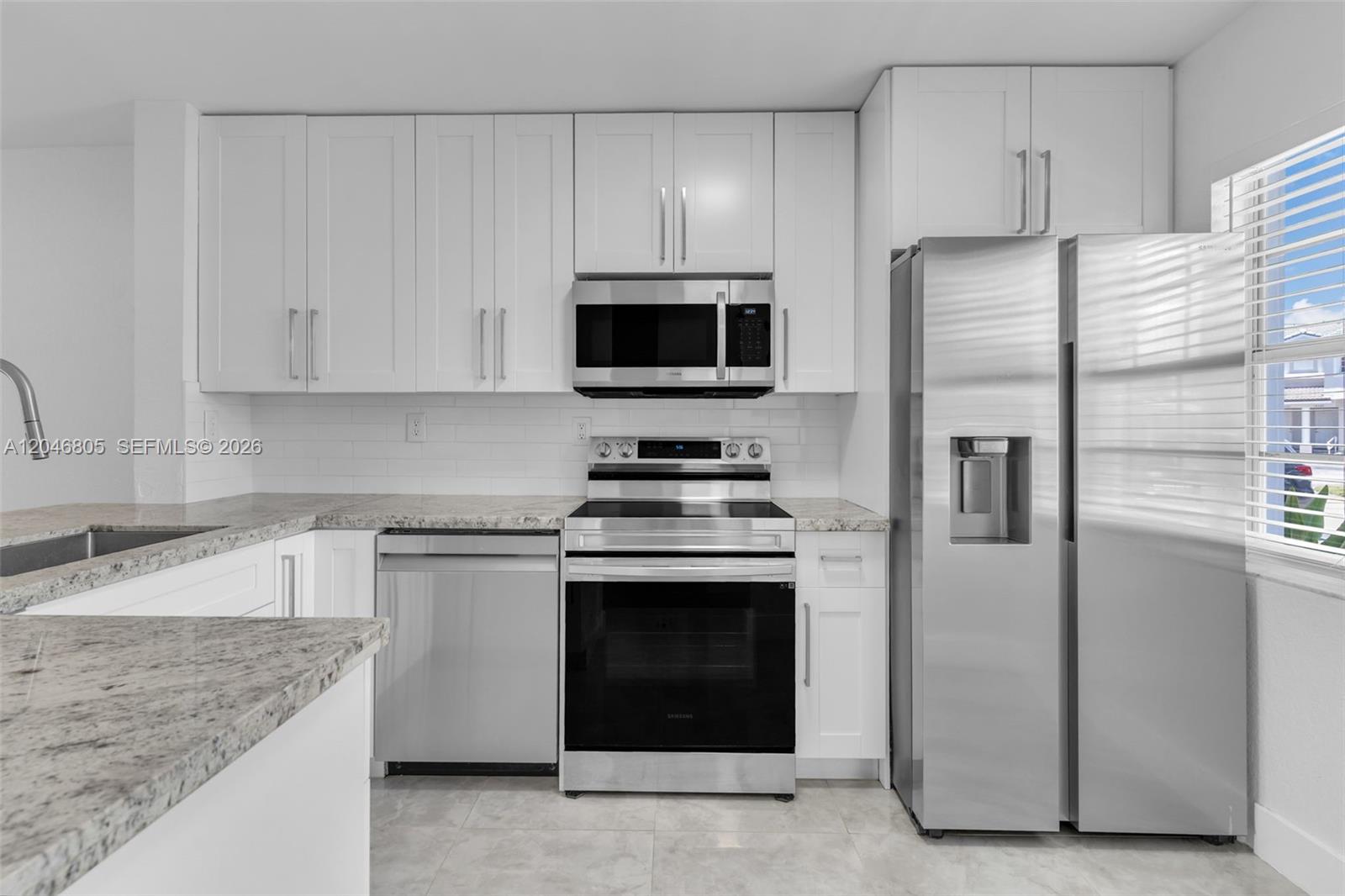 A kitchen features white cabinets, stainless steel appliances, and light-colored granite countertops — 14231 SW 120th Ct # 11, Miami FL 33186, MIAMI, FL