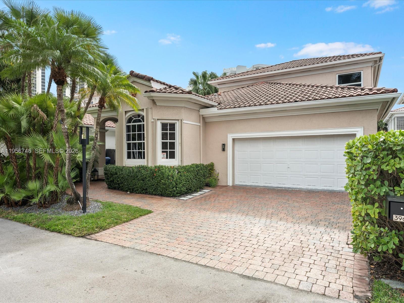 A beige house with a tiled roof, a two-car garage, and a brick-paved driveway — 3960 194th Trl, Sunny Isles Beach FL 33160, SUNNY ISLES BEACH, FL