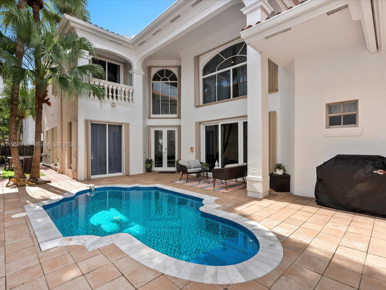 A two-story house exterior features a swimming pool, patio furniture, and palm trees — 3960 194th Trl, Sunny Isles Beach FL 33160, SUNNY ISLES BEACH, FL