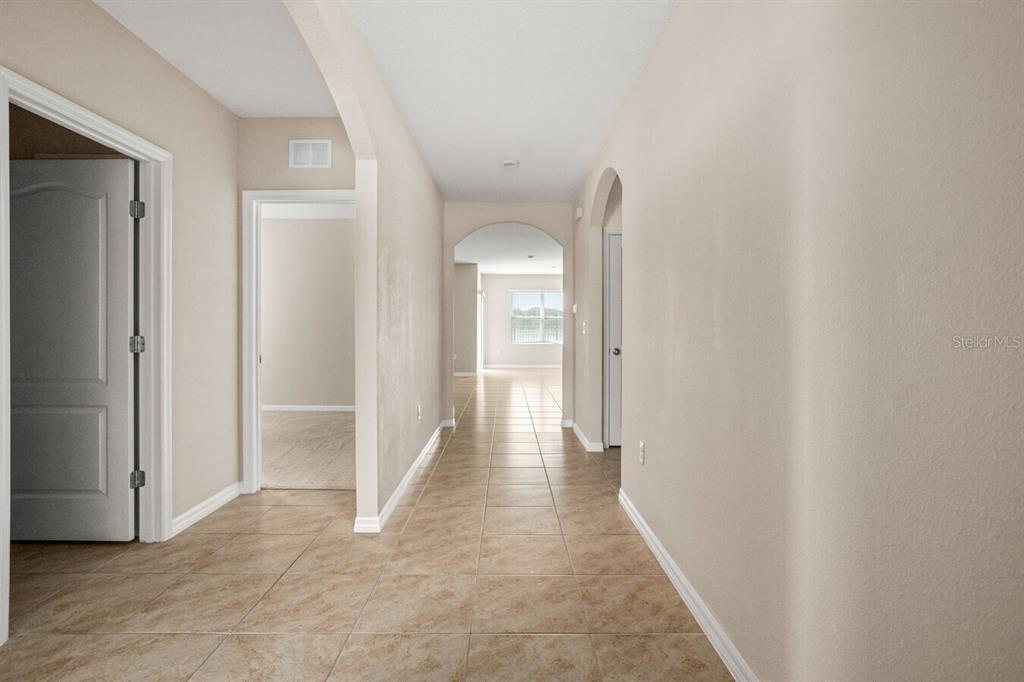 A tiled hallway leads to an arched entryway with a view of a bright room — 1112 FOX PATH, DAVENPORT, FL
