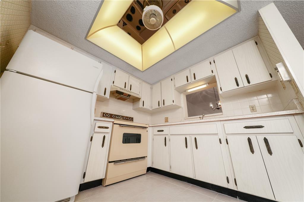 A kitchen features white cabinets, a beige oven, and a recessed ceiling light fixture — 1450 HEATHER RIDGE BOULEVARD UNIT 307, DUNEDIN, FL