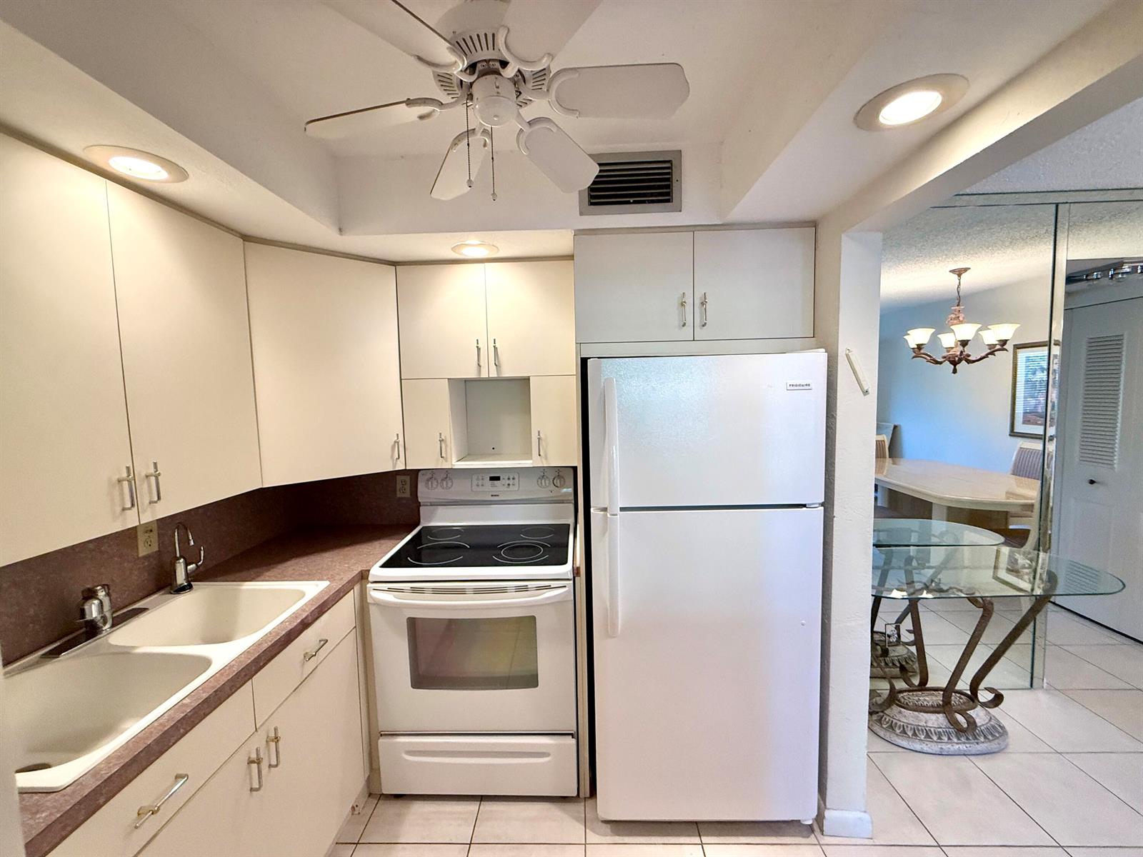 A kitchen features white appliances, light-colored cabinetry, laminate countertops, and a ceiling fan — 2009 Berkshire A, Deerfield Beach FL 33442, DEERFIELD BEACH, FL