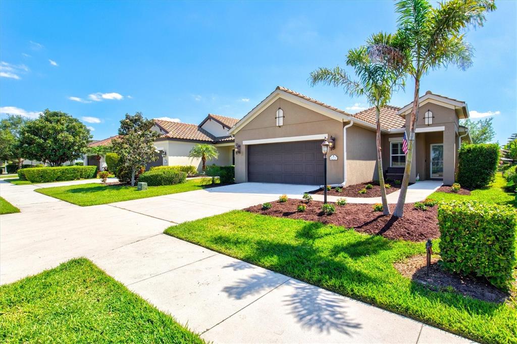 A single-story suburban house with a two-car garage, palm trees, and a landscaped front yard — 4207 AZURITE WAY, BRADENTON, FL