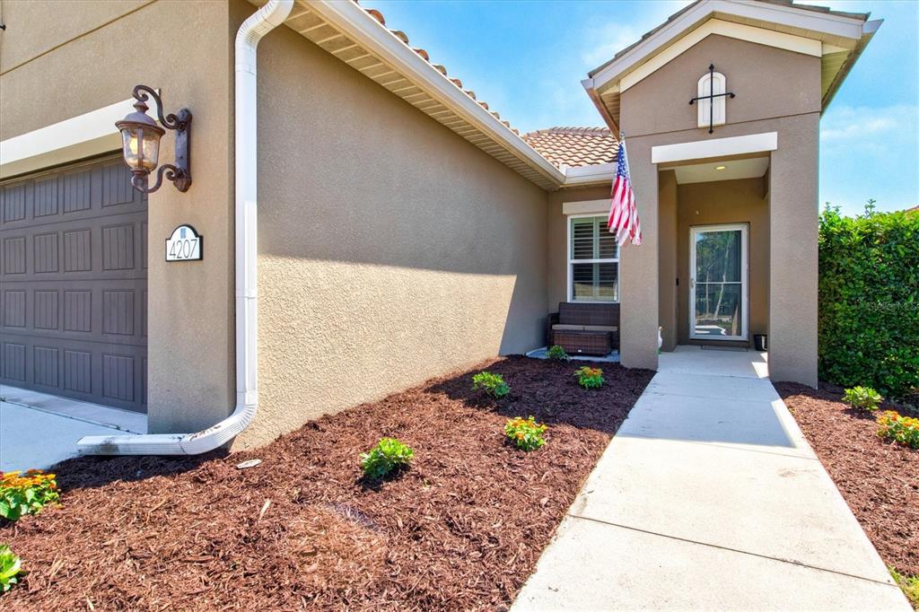 The exterior of a house features a tan stucco facade, a garage, and a walkway — 4207 AZURITE WAY, BRADENTON, FL