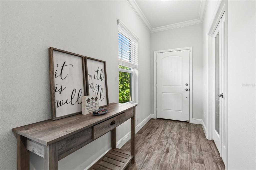 A wooden console table sits in a bright entryway with wood-look tile flooring — 4207 AZURITE WAY, BRADENTON, FL