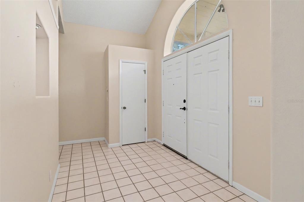 An entryway features a tiled floor, a white door, and a double front door with an arched window — 875 GABRIEL AVENUE NE, PALM BAY, FL