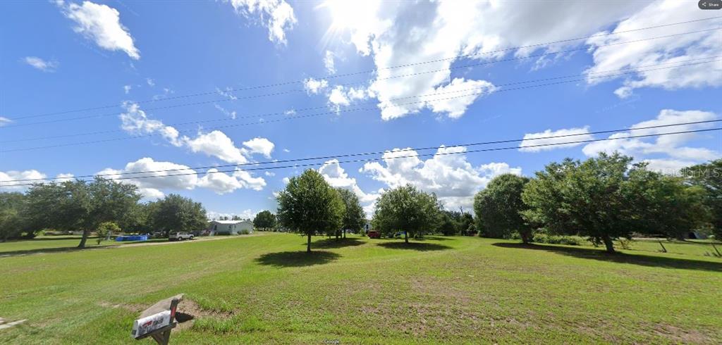 A wide, grassy vacant lot features several mature trees under a bright, partly cloudy sky — TIGER LAKE RD, LAKE WALES, FL