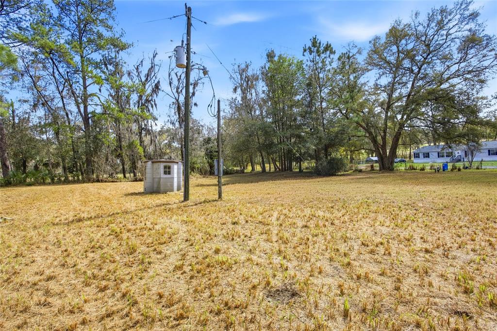 A grassy lot features a small utility shed and two utility poles under a blue sky — 7900 W HIGHWAY 326, OCALA, FL
