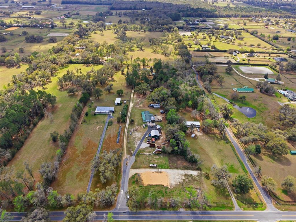 An aerial view shows a rural property with multiple buildings, pastures, and trees near a road — 7900 W HIGHWAY 326, OCALA, FL