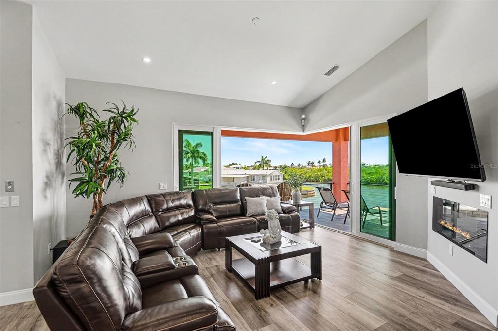 A living room features a brown leather sectional, a fireplace, and sliding doors to a balcony — 604 TAHITI COURT, PUNTA GORDA, FL