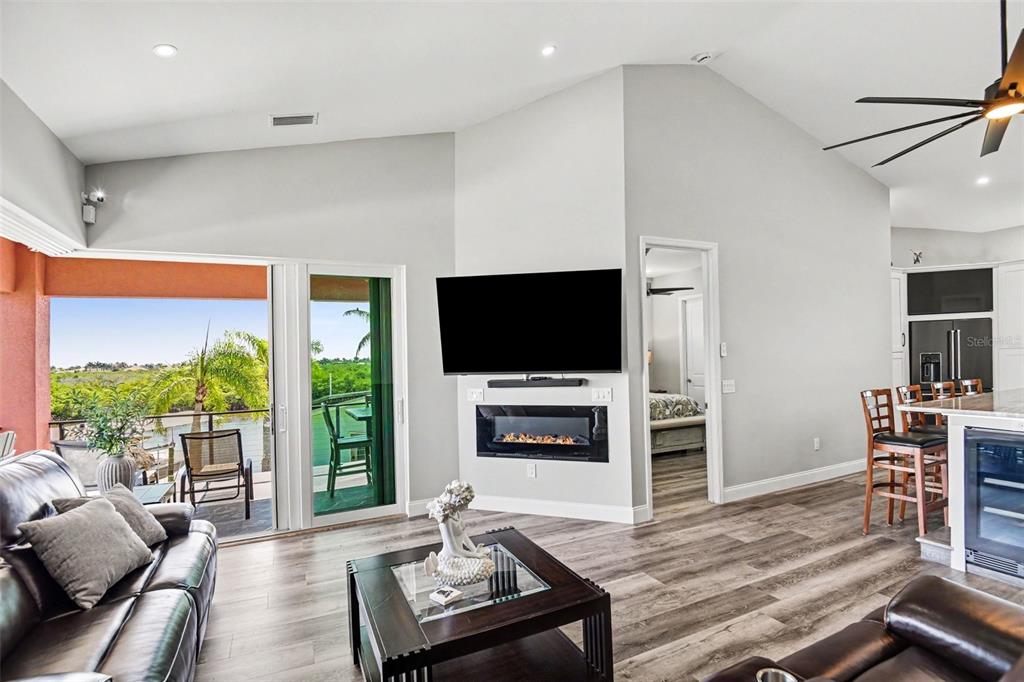 A living room features a wall-mounted television, an electric fireplace, and sliding glass balcony doors — 604 TAHITI COURT, PUNTA GORDA, FL