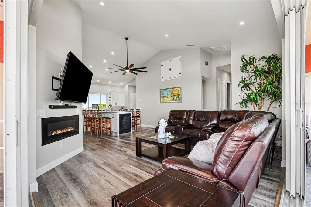 A living room with a fireplace, wall-mounted television, leather sectional, and an open kitchen — 604 TAHITI COURT, PUNTA GORDA, FL