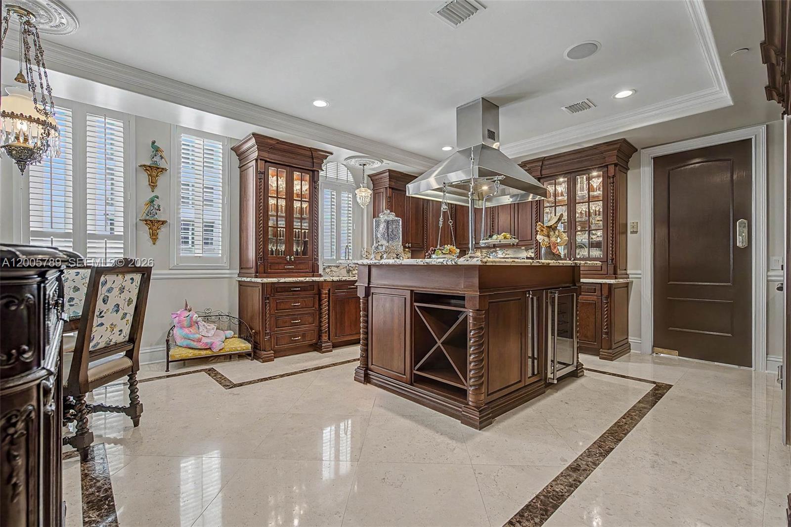 A kitchen features dark wood cabinetry, a central island with a range hood, and tile flooring — 600 Coral Way # 5, Coral Gables FL 33134, CORAL GABLES, FL